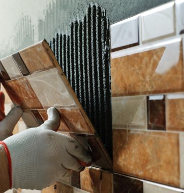 Laying Ceramic Tiles. Tiler placing ceramic wall tile in position over adhesive